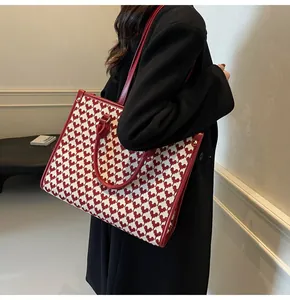 Macro detail of red and white heart jacquard tote bag with polished red leather trim