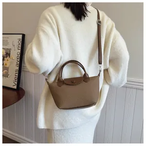 Detail of brown woven texture bag with leather flap and detachable strap on a model
