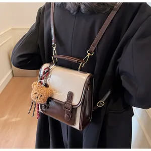 Detalle de cerca del bolso vintage beige y marrón con un lindo colgante de oso de peluche