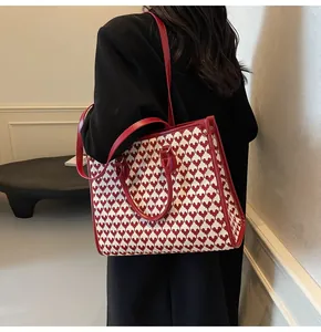 Detail of red and white heart-patterned tote bag with leather trim on model
