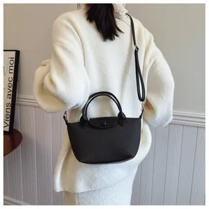 Close-up of black woven texture bag featuring leather flap and adjustable crossbody strap