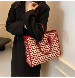 Macro view of bridal tote bag featuring red heart jacquard fabric and leather strap