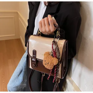 Bolso de cuero retro bicolor con colgante de oso y detalle de marca fashion leather