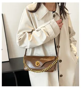 Detail showing vintage brown leather bag texture with gold chain and circular turn lock