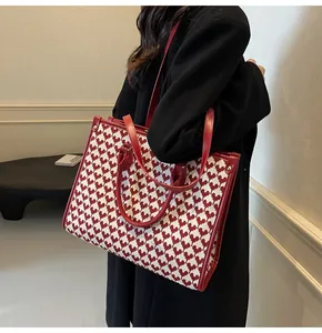 Model wearing a red heart pattern tote bag with leather trim and shoulder strap