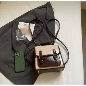 Vista detallada de una mini mochila vintage bicolor con hebillas magnéticas y fondo elegante