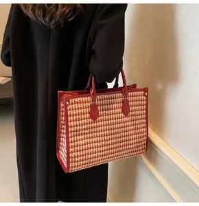 Detail of red houndstooth tote bag featuring premium leather handles and metal rivets