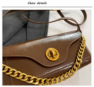 Close-up of vintage dark brown leather bag with gold buckle and chain strap detail