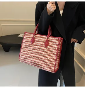 Close-up of red houndstooth tote bag with premium leather handles and metal studs