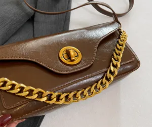 Detail view of dark brown textured leather bag with gold buckle and chunky chain strap