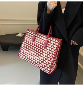 Detail of red heart-pattern woven tote with leather trim and metallic rivets
