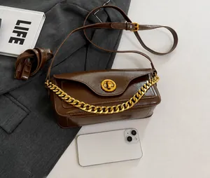 Detail of dark brown retro shoulder bag with gold ring buckle and metallic chain strap