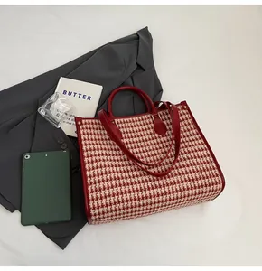Detail of red houndstooth tote bag with leather handles and gold-tone hardware