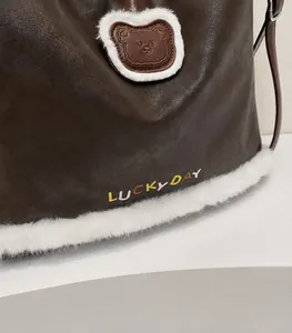 Detail of lychee pattern leather and white faux fur trim on a brown tote bag