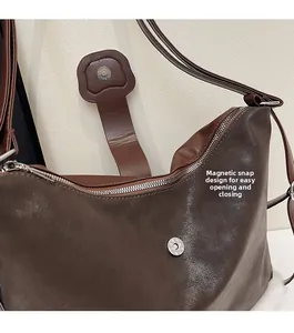 Detail view of the brown leather tote bag showing a magnetic snap closure and zipper