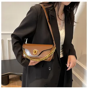 Detail of a brown leather shoulder bag with a gold ring clasp and chunky metal chain strap