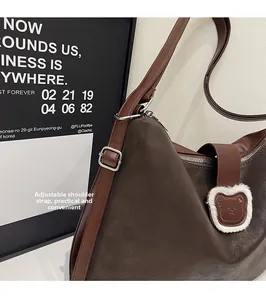 Macro shot of dark brown tote featuring adjustable strap and plush bear buckle detail