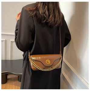 Detail of a brown glossy faux leather shoulder bag with gold chain and metal twist lock