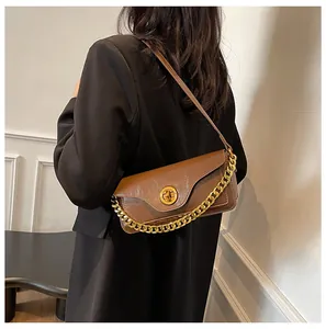 Brown leather underarm bag with gold chain and ring lock shown on model shoulder