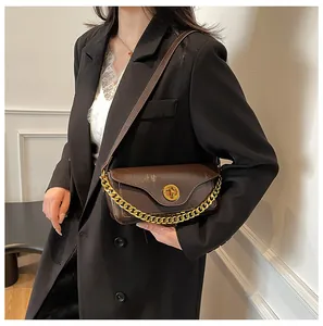 Detail of dark brown leather underarm bag with gold chain and circular twist lock closure