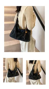 Detail of a black textured hobo bag with gold sphere charm on a stylish model