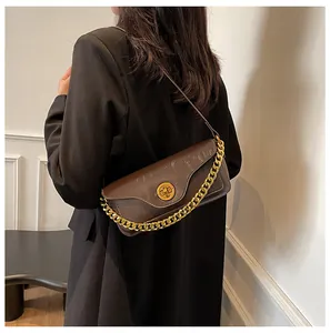 Brown crocodile-textured baguette bag with a chunky gold chain strap and metal lock