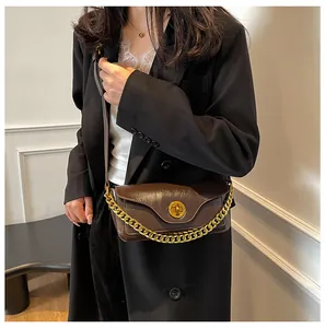 Detail of a dark brown leather crossbody bag with a gold metal lock and chain strap