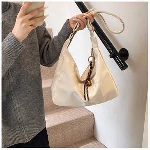 Detail of hobo bag with micro-wrinkled texture and golden bell charm accessory