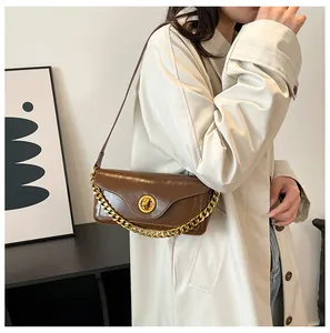 Brown vintage shoulder bag with golden chain and circular twist lock detail on white coat