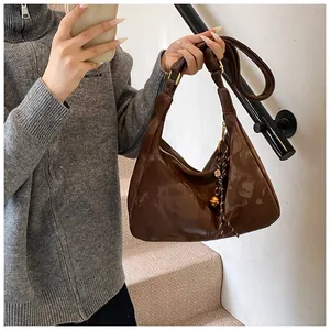 Close-up of brown glossy patent leather hobo bag with gold hardware on a staircase