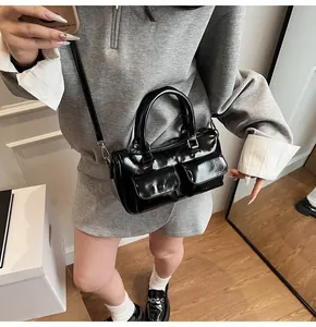 Glossy black Boston bowling bag with front pockets shown being carried by a model
