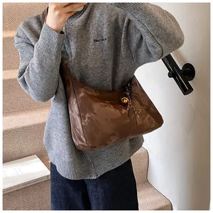 Close-up of brown patent leather hobo bag featuring glossy texture and golden hardware
