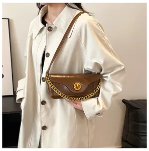Detail of dark brown patent leather bag with gold circular lock and thick chain