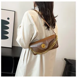 Detailed view of brown retro underarm bag with gold ring twist lock and dual chain strap