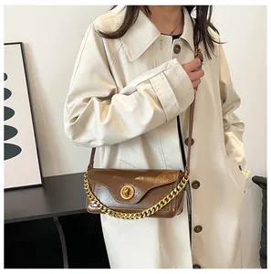 Close-up of caramel brown PU leather shoulder bag with a bold gold chain handle