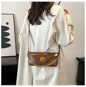 Detail of dark brown leather handbag with gold twist lock and decorative chain strap