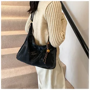 Detail of black large-capacity hobo bag with braided rope strap and gold sphere charm