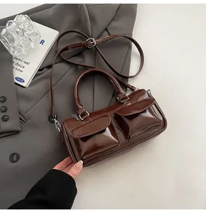 Detail of dark brown patent leather handbag with dual front pockets and silver hardware