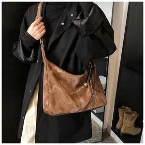 Brown cloud-textured large hobo bag with wide strap styled on a model in a black coat