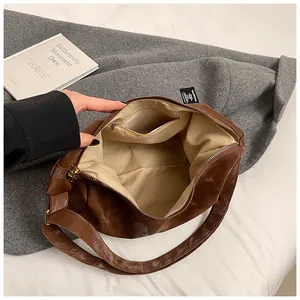 Internal view of the brown leather shoulder bag featuring beige lining and a zipped pocket