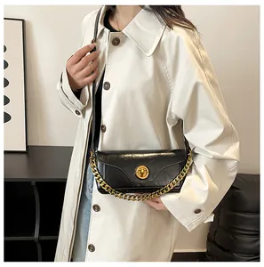 Detail of black patent leather underarm bag with gold twist lock and chunky chain link