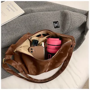 Spacious interior of dark brown shiny leather handbag showing daily items and gold hardware