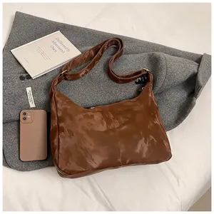 Macro detail of dark brown glossy PU leather tote bag with stylish pleated texture