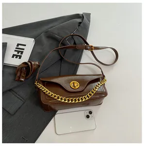 Detail of dark brown leather underarm bag with gold chain and vintage twist lock