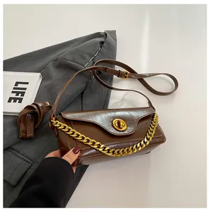 Detail of dark brown faux leather underarm bag with gold chain and ring twist lock