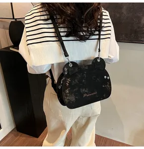Dettaglio della borsa a tracolla nera a forma di orso con scritta Princess e rivetti