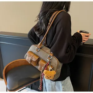 Detail of vintage canvas and leather Boston bag with plush bear and scarf accessories
