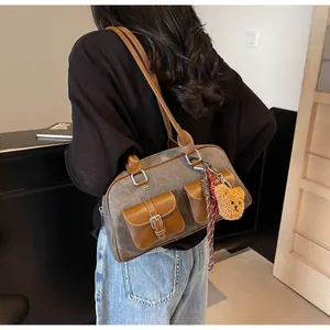 Detail of Boston bag showing gray canvas拼接brown leather with plush bear pendant