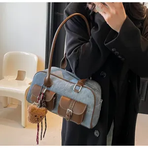 Detail of denim and leather Boston bag with external flap pockets and teddy charm