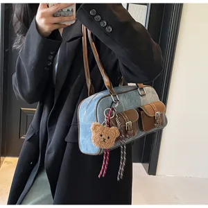 Detail view of vintage blue denim Boston bag with brown leather trim and plush bear charm